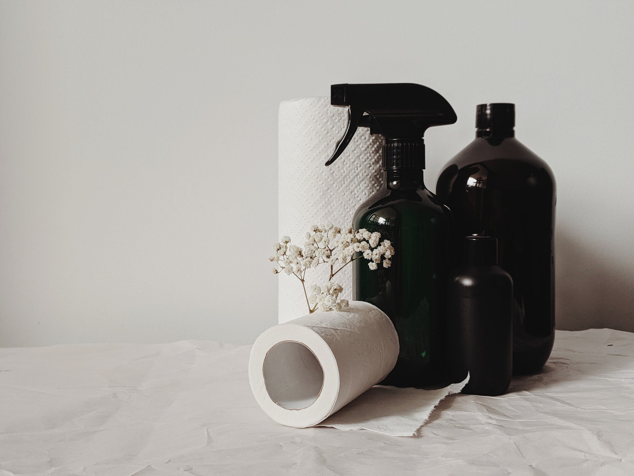 Rolls of tissue and cleaning bottles on white background